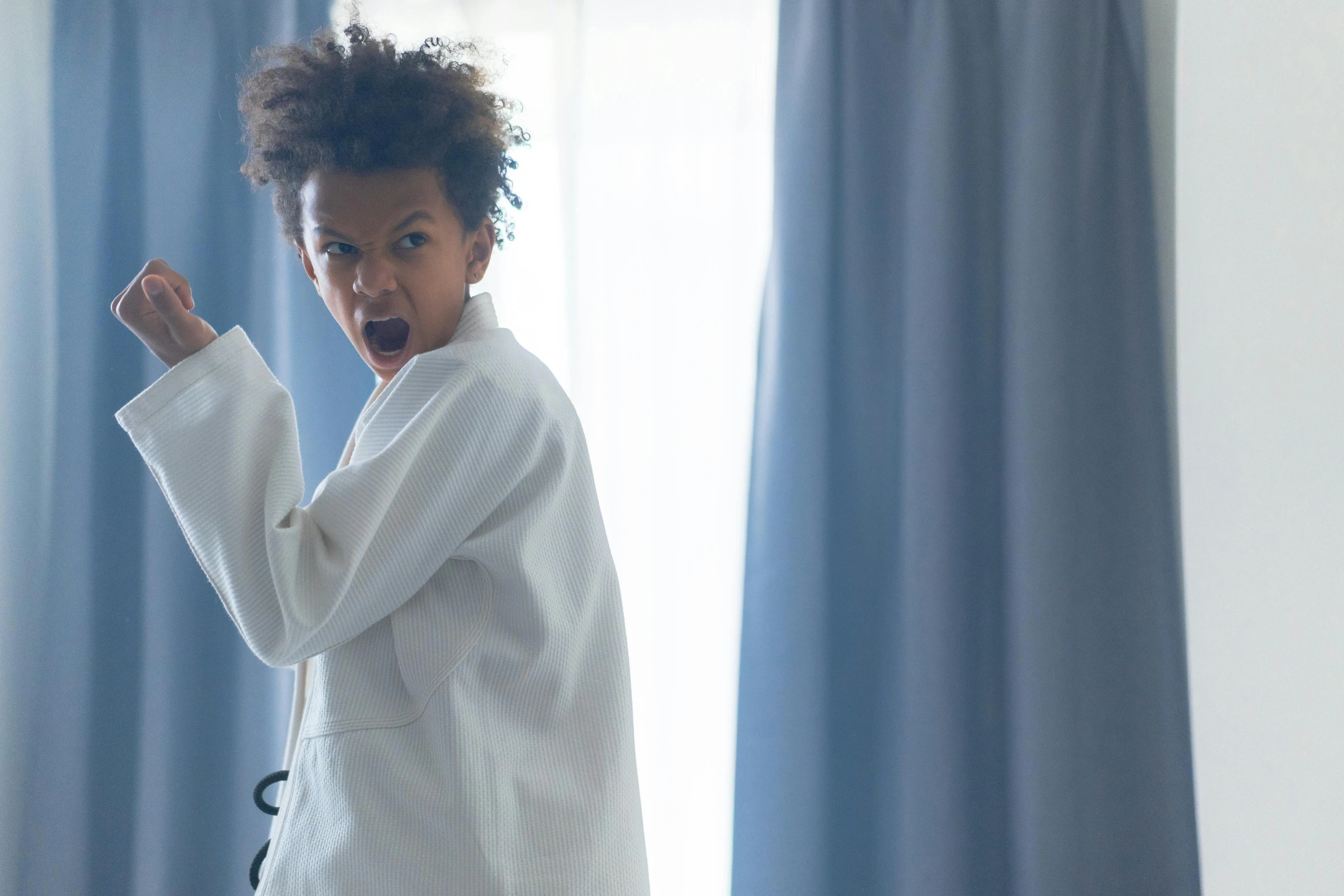 a little girl standing in front of a window, an album cover, inspired by Théodule Ribot, pexels contest winner, antipodeans, getting ready to fight, at the hospital in patient gown, aggressive stance, african american young woman