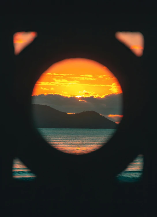 the sun is setting over a body of water, pexels contest winner, precisionism, round window, abel tasman, with laser-like focus, high quality photo