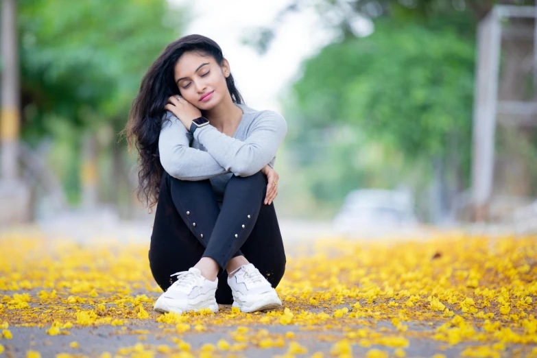 a woman sitting in the middle of a field of yellow flowers, pexels contest winner, hurufiyya, indian girl with brown skin, background image, covered in fallen leaves, college