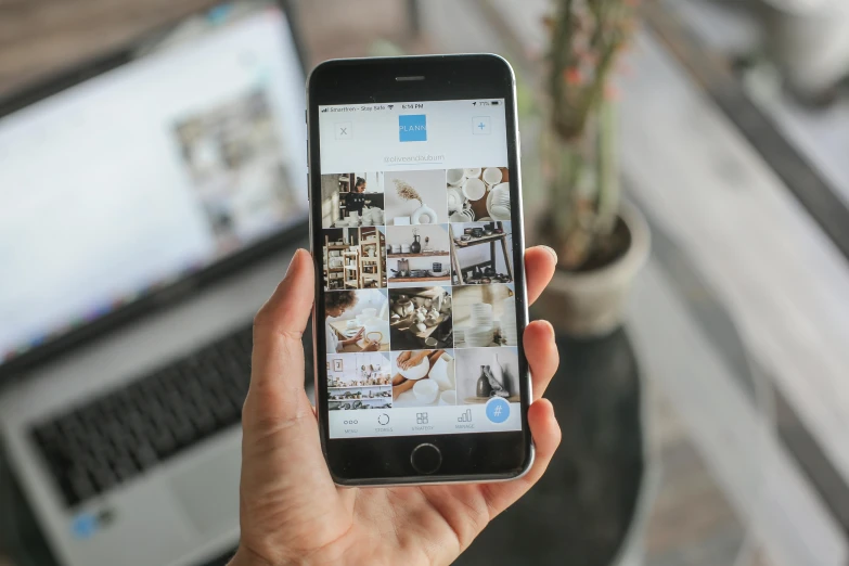 a person holding a cell phone in front of a laptop, a picture, trending on unsplash, 9 9 designs, instagram post 4k, brown, instant photography