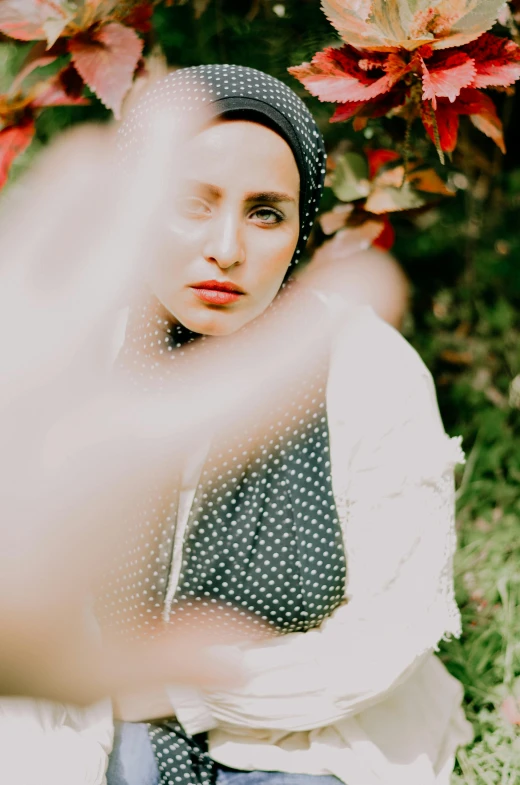 a woman sitting on top of a lush green field, a colorized photo, inspired by Elsa Bleda, trending on pexels, renaissance, detailed face of an arabic woman, polka dot, cinematic outfit photo, in the garden