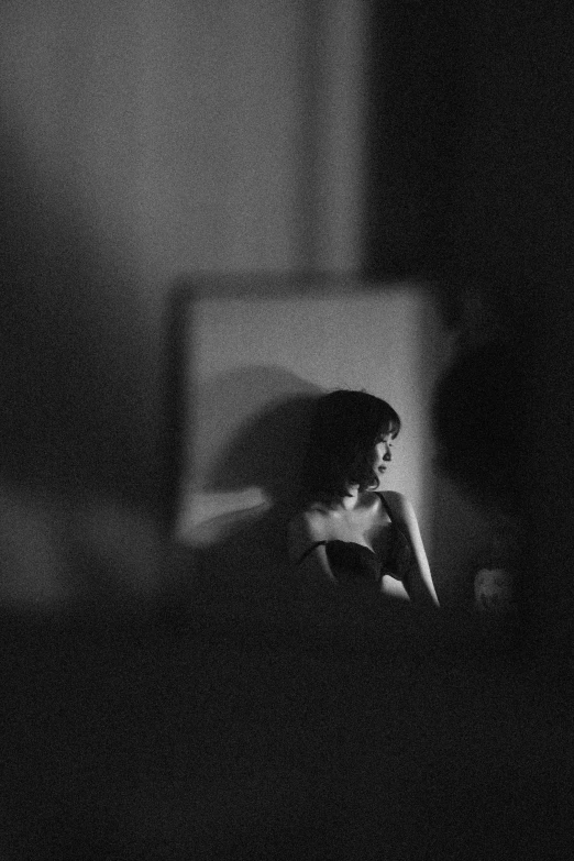 a woman sitting in front of a mirror, a black and white photo, inspired by Nan Goldin, unsplash, silhouette :7, studio medium format photograph, girl with black hair, someone sits in bed