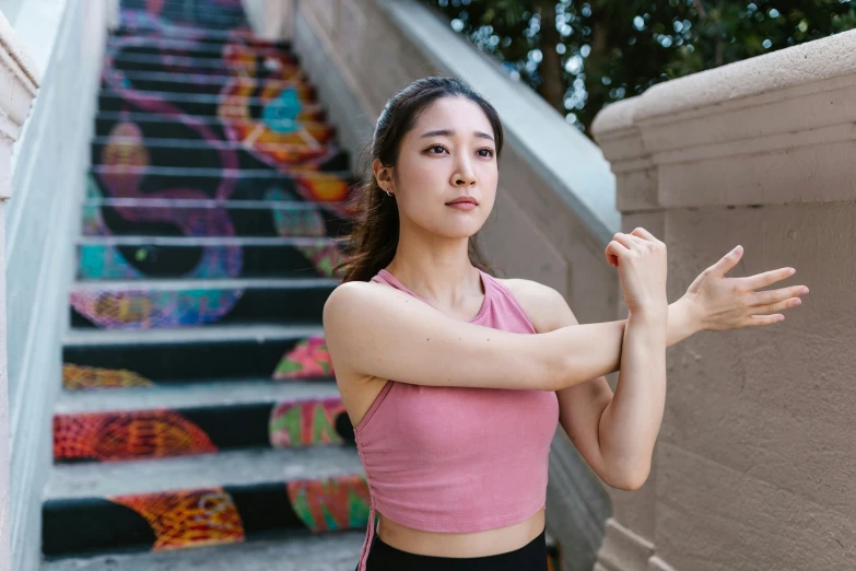 a woman standing in front of a set of stairs, inspired by helen huang, pexels contest winner, showing off biceps, tendu pose, korean girl, background image