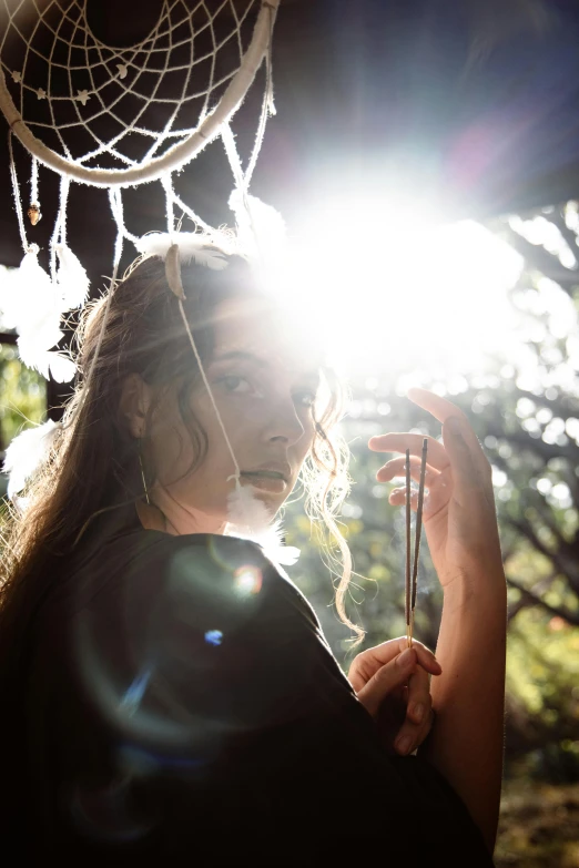 a woman that is standing in the sun, a portrait, by Heather Hudson, unsplash, happening, dreamcatchers, lights inside, holding a magic staff, shot with sony alpha