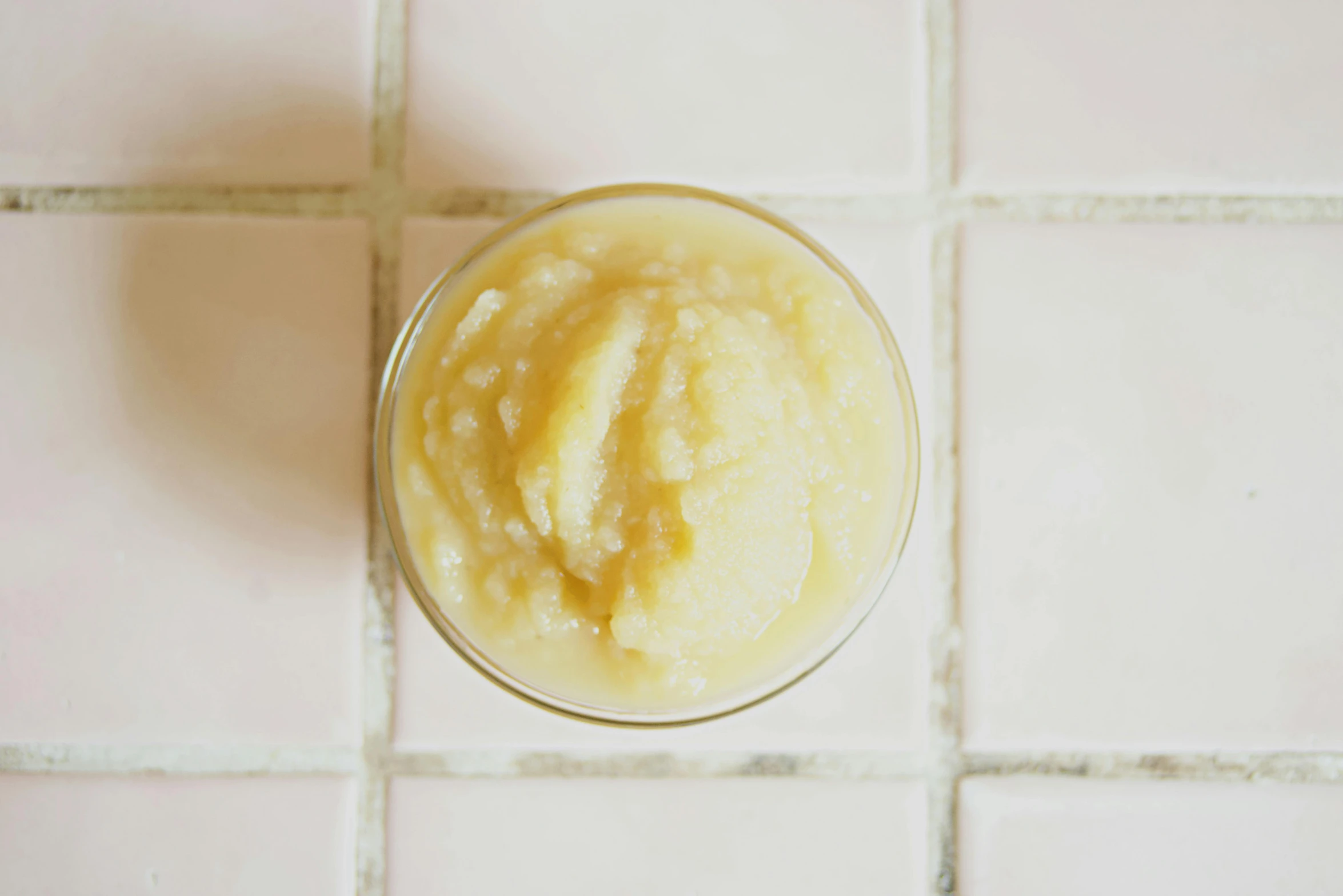 a close up of a bowl of food on a tiled floor, by Carey Morris, unsplash, jelly - like texture, light yellow, organics, slush