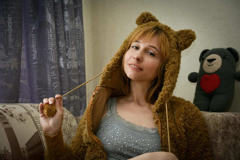 a woman sitting on a couch next to a teddy bear, an album cover, by Julia Pishtar, furry art, cosplay photo, in a hoodie, metart, cat ears and cat tail!