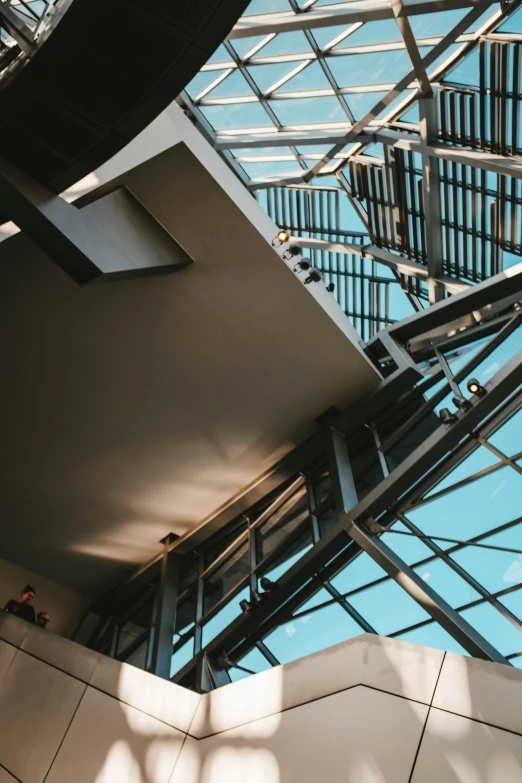a staircase in a building with a blue sky in the background, inspired by Zaha Hadid, unsplash contest winner, mechanical superstructure, light breaks through the roofs, inside a library, medium close up shot