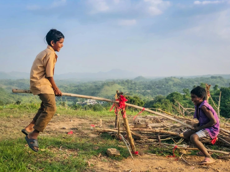 a couple of people that are standing in the grass, pexels contest winner, land art, sri lankan landscape, kids playing, holding a wooden staff, working hard