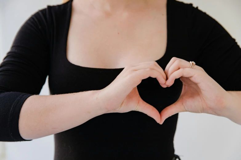 a woman making a heart with her hands, unsplash, wearing a black shirt, background image, medium format, large)}]