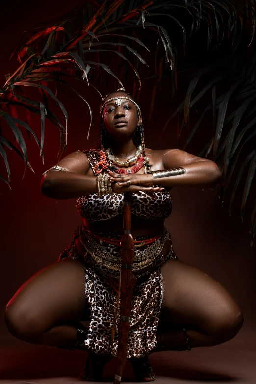 a woman sitting on the ground with a sword in her hand, an album cover, by Ingrida Kadaka, pexels contest winner, afrofuturism, regal and proud robust woman, loin cloth, studio photo, wearing an african dress