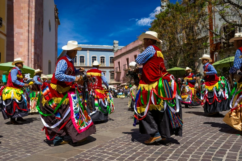 a group of people that are standing in the street, by Julia Pishtar, pexels contest winner, quito school, tribal dance, square, on a sunny day, multicolor