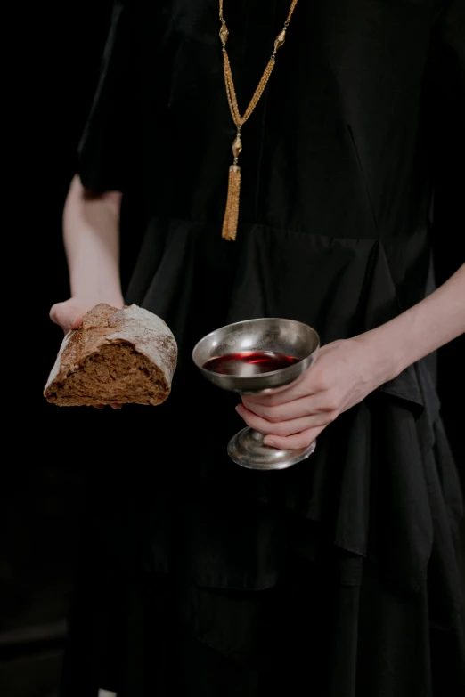 a woman in a black dress holding a piece of bread, inspired by Master of the Legend of Saint Lucy, unsplash, wearing robes of silver, bloody, overturned chalice, ignant