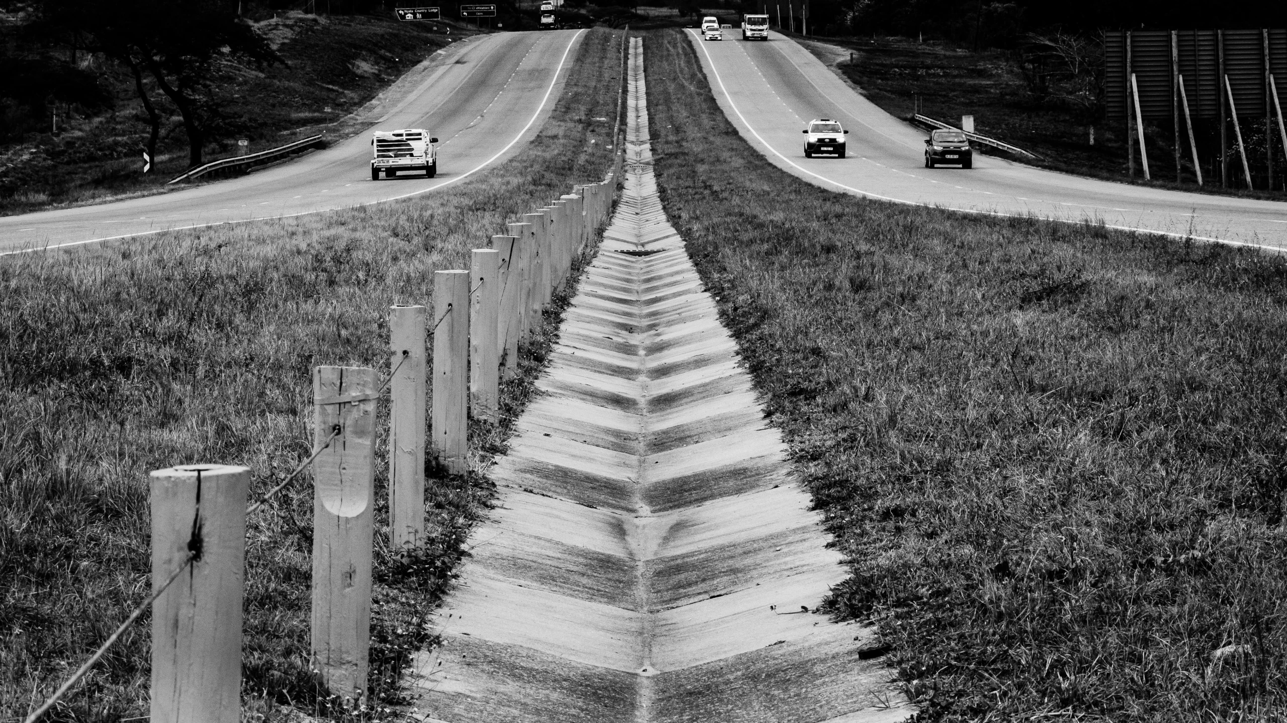 a black and white photo of a long road, a black and white photo, by Adam Chmielowski, conceptual art, 'action lines '!!!, guardrail, the merge, in line