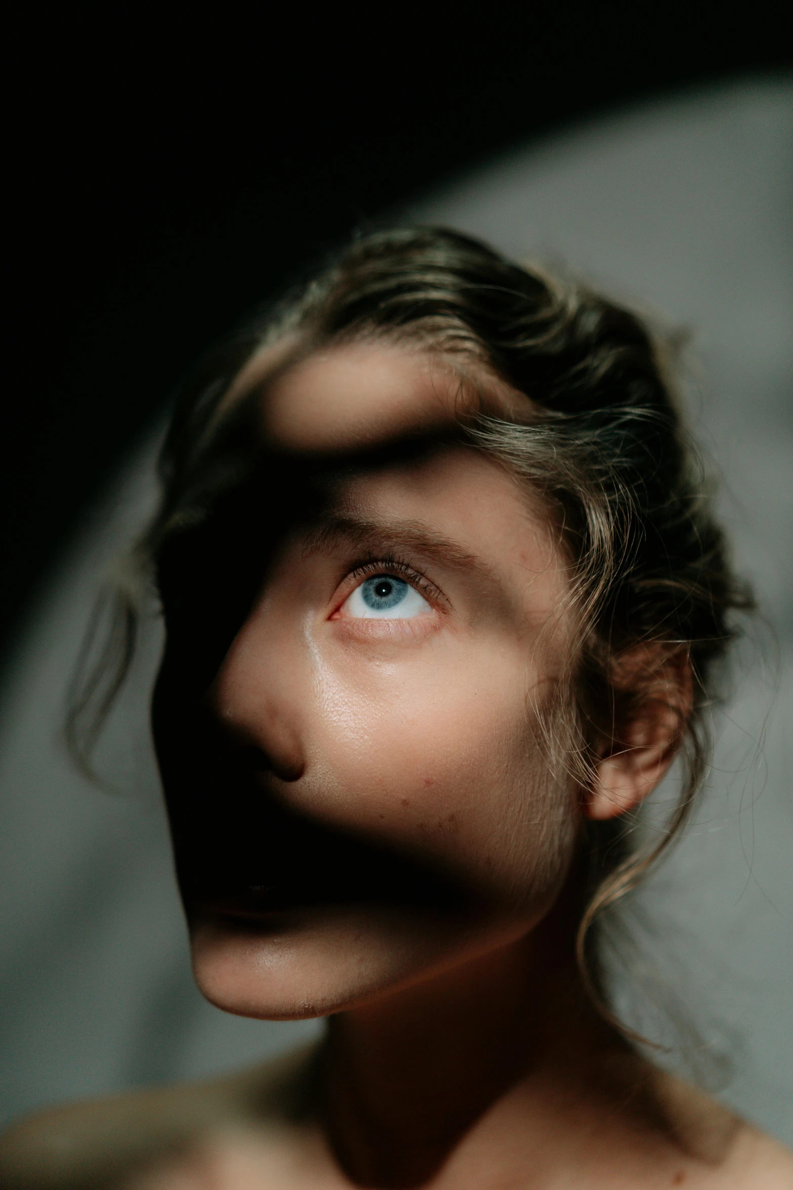 a close up of a person with blue eyes, an album cover, by Adam Marczyński, trending on pexels, female image in shadow, halfbody portrait, soft internal light, weird portrait angle