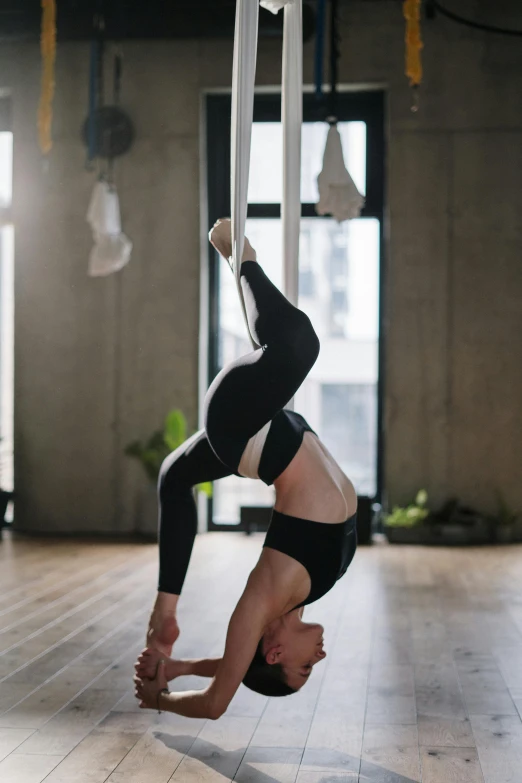 a woman doing a handstand in a gym, pexels contest winner, arabesque, hanging from white web, profile image, lotus pose, webbing