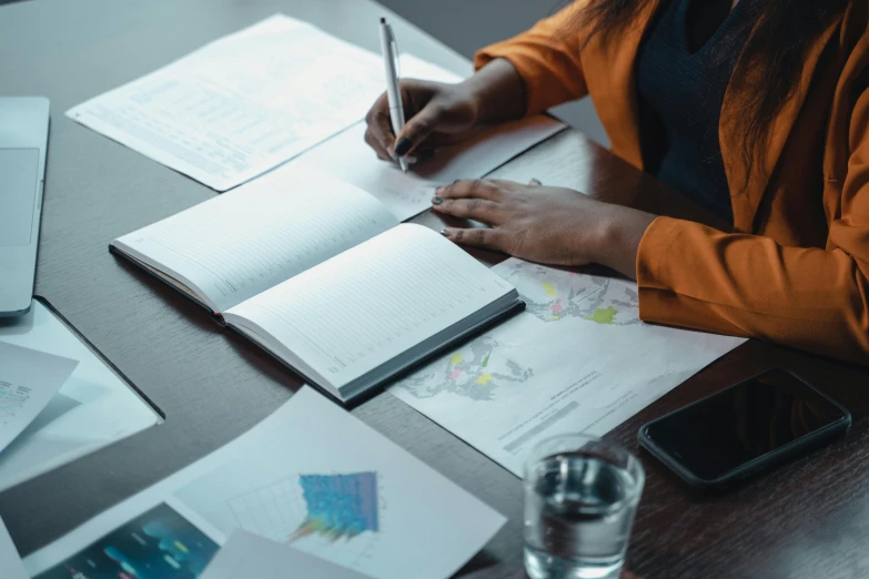 a woman sitting at a table writing in a notebook, pexels contest winner, reading engineering book, avatar image, court session images, a high angle shot