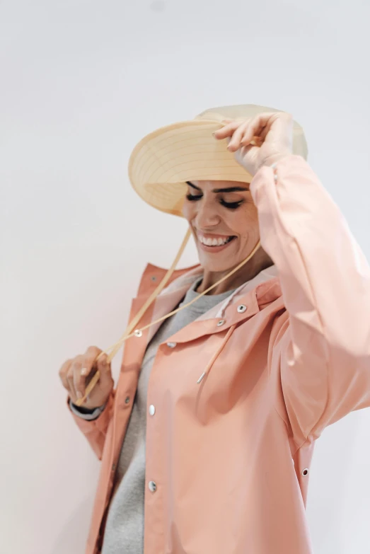 a woman wearing a pink raincoat and a straw hat, trending on unsplash, white background, laughing, wearing off - white style, met collection