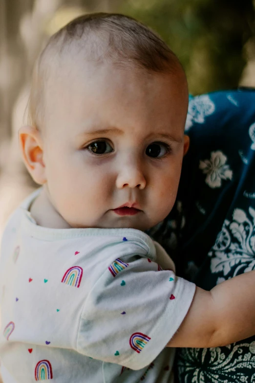 a woman holding a baby in her arms, a portrait, inspired by Myles Birket Foster, unsplash, detail shot, proud serious expression, multi colour, spots