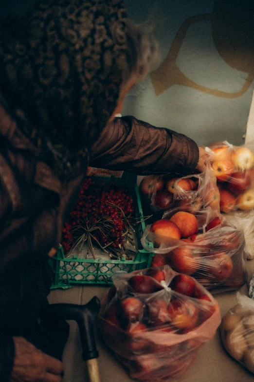 a woman standing in front of a counter filled with food, by Daniel Lieske, pexels, red apples, permaculture, photo of a black woman, medium shot taken from behind