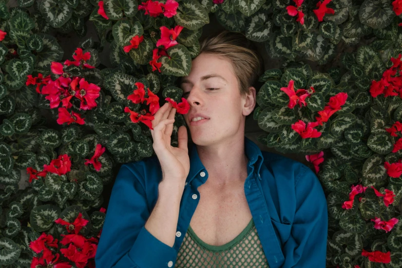 a woman laying on a bed of flowers talking on a cell phone, by Julia Pishtar, pexels contest winner, androgynous face, green and red plants, asleep, sydney sweeney