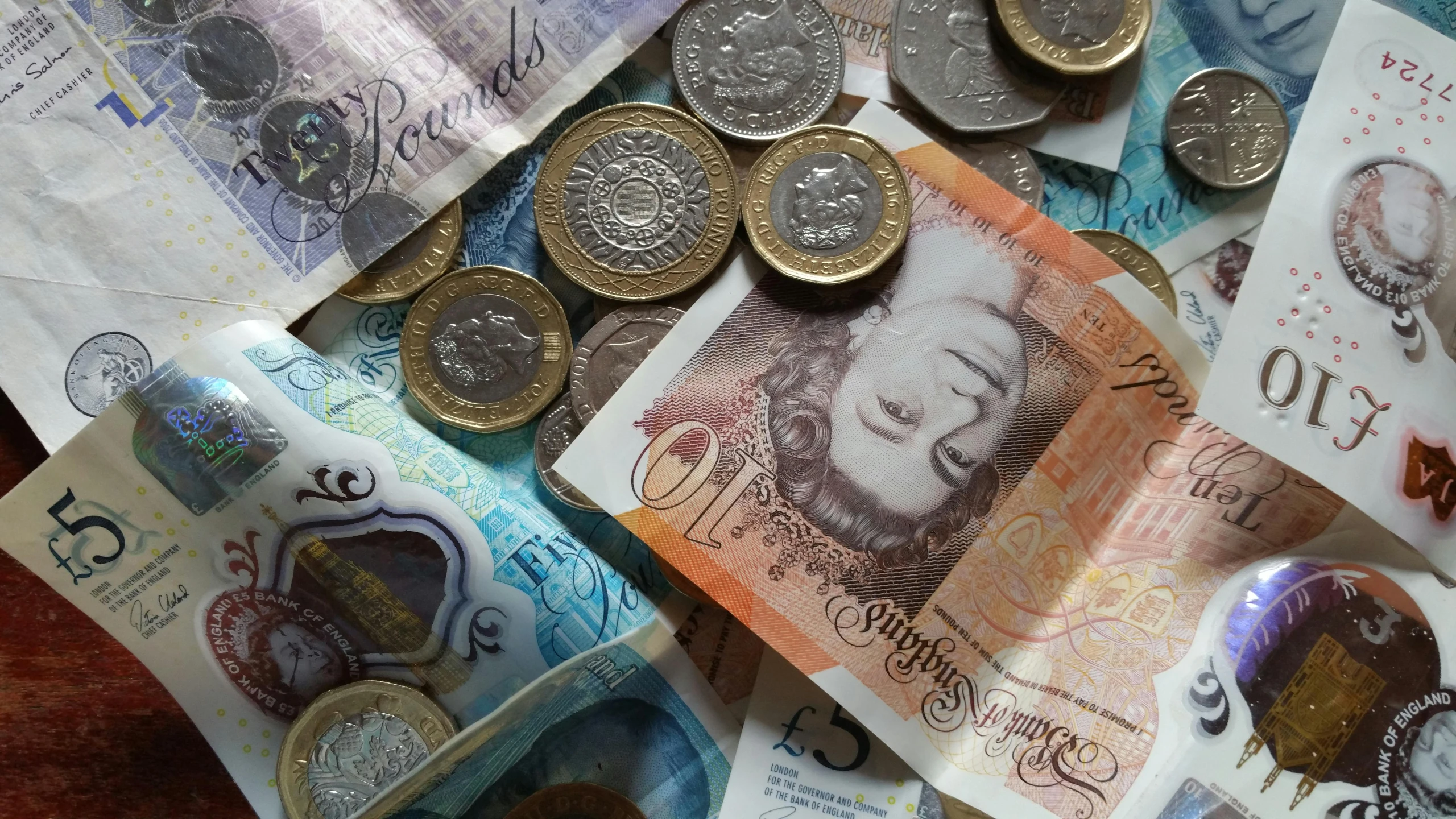 a pile of money sitting on top of a table, by Lee Loughridge, pexels, emma bridgewater and paperchase, photo of head, britain, diverse