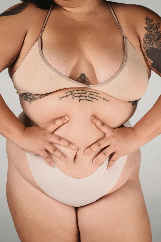 a woman in a bikini posing for a picture, a tattoo, by Jessie Alexandra Dick, trending on pexels, folds of belly flab, heavy gesture style closeup, thick outline, promo image