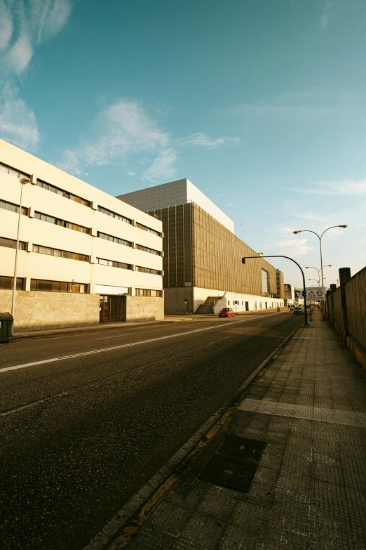 a large white building sitting on the side of a road, by Carlo Martini, unsplash, brutalism, warehouses, brown, spanish, low quality photo