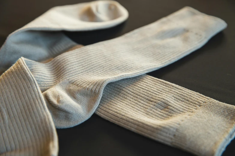 a pair of socks sitting on top of a table, inspired by Sarah Lucas, unsplash, renaissance, detail texture, corduroy, silver，ivory, ground - level medium shot