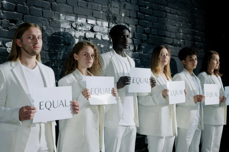 a group of people standing next to each other holding signs, by Emma Andijewska, trending on unsplash, antipodeans, wearing futuristic white suit, mix of ethnicities and genders, white ribbon, equations