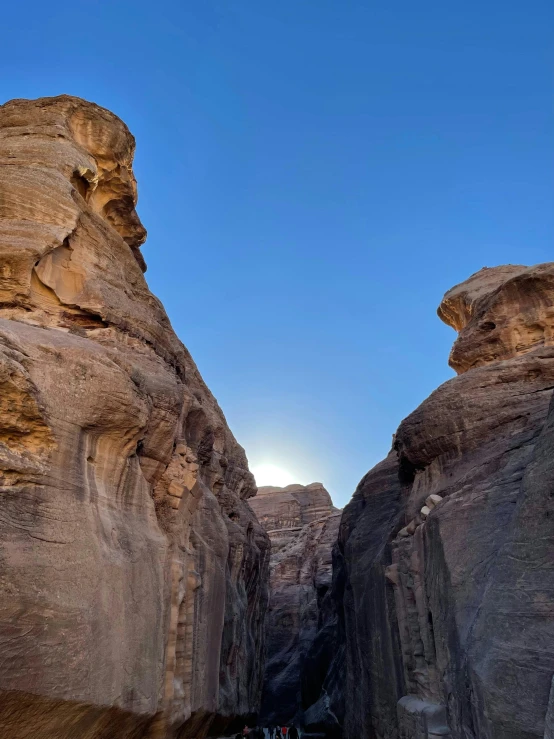 a group of people walking through a narrow canyon, with the sun shining on it, arabian features, slide show, stacked image