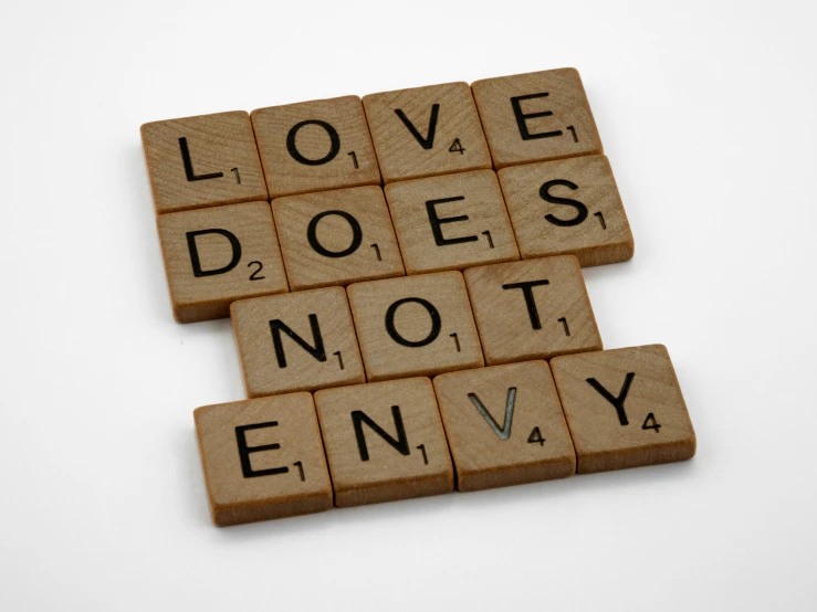wooden scrabbles spelling love does not envy, an album cover, inspired by János Valentiny, pixabay, nendoroid, refer to late timothy leary, ancient evil letters, dezeen