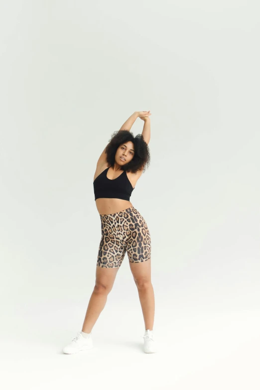 a woman in a black top and leopard print shorts, by Sam Charles, trending on pexels, renaissance, crop yoga short, full body with dynamic pose, curls and curves, full product shot