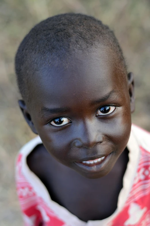 a close up of a child with blue eyes, an album cover, by James Warhola, hurufiyya, masai, welcoming grin, porcelain skin ”