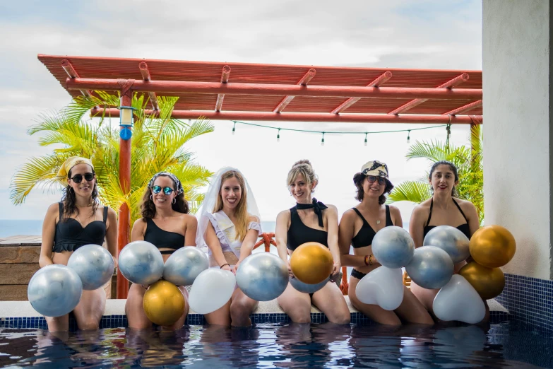 a group of women sitting next to each other in a pool, decorated, 6 toucan beaks, on rooftop, sol retreat