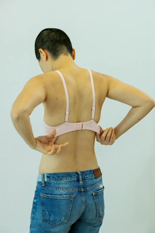 a woman standing with her back to the camera, a colorized photo, inspired by Ren Hang, unsplash, sport bra, 奈良美智, pink, ergonomic