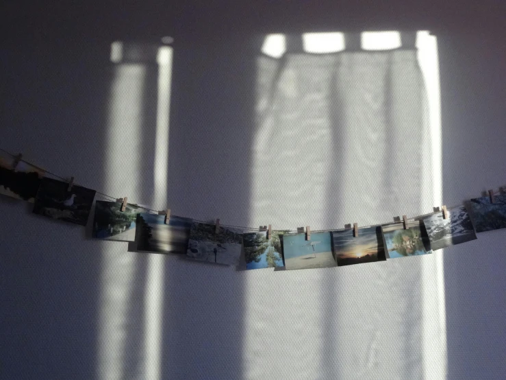 a picture hanging on a clothes line in front of a window, a polaroid photo, inspired by Elsa Bleda, unsplash, light and space, in a row, studio ghibli sunlight, instant photograph of the sky, 1990s bedroom