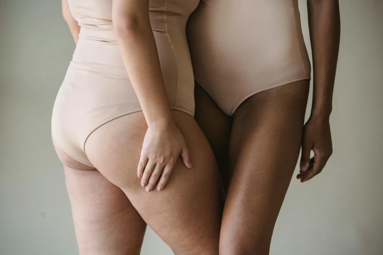 a couple of women standing next to each other, by Emma Andijewska, thighs close up, creamy skin, diverse, tummy