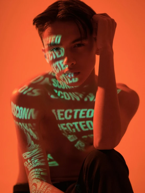 a man with the words projected on his body, by Andrew Stevovich, trending on pexels, holography, :: madison beer, non binary model, orange lights, editorial portrait