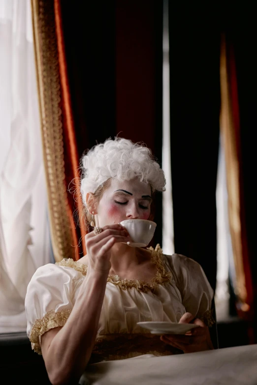 a woman sitting in front of a window eating a piece of cake, inspired by Pietro Longhi, pexels contest winner, rococo, white face paint, next to a cup, ( ( theatrical ) ), performance art