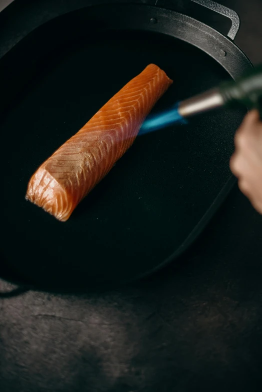 a person cooking a piece of salmon in a frying pan, by Matthias Stom, trending on pexels, carving, paul barson, dipstick tail, high quality photo