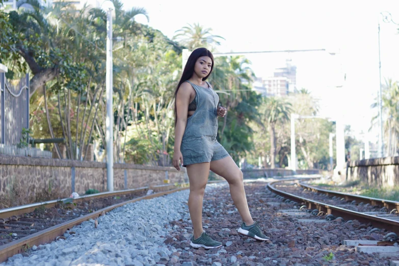 a woman is standing on a train track, by Judith Gutierrez, bra and shorts streetwear, alanis guillen, portait image, full body shot 4k