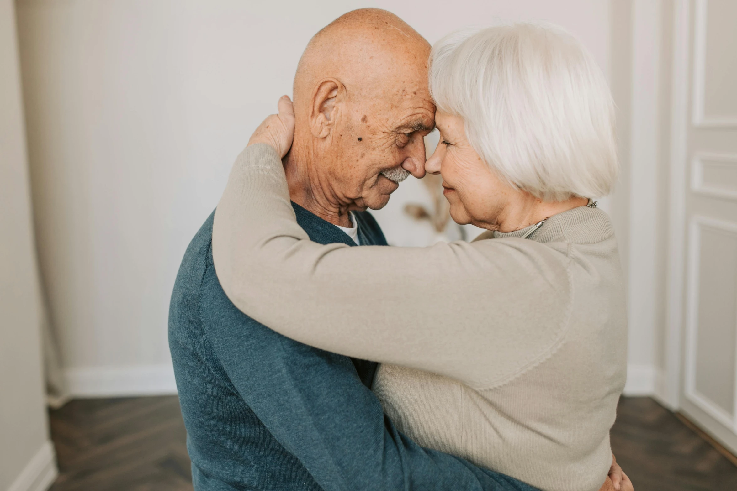 an older couple embracing each other in a living room, pexels contest winner, profile image, background image, paul barson, incredibly cute
