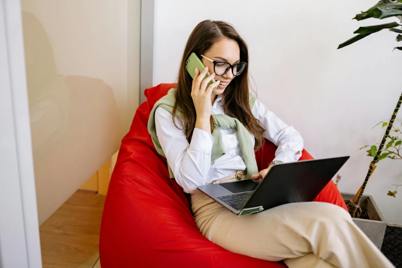 a woman sitting on a bean bag chair talking on a cell phone, trending on pexels, figuration libre, sitting at a computer, professional photo, maintenance, girl wearing round glasses