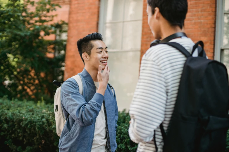 a couple of men standing next to each other, pexels contest winner, happening, college students, hand on his cheek, gemma chen, reaching out to each other