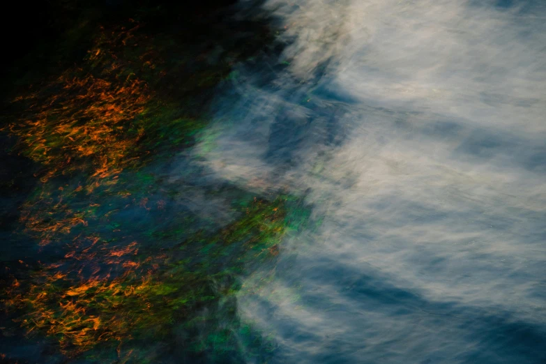 a blurry photo of a body of water, an album cover, inspired by George Frederic Watts, unsplash, lyrical abstraction, flaming leaves, multi - coloured, ignant, cloud iridescence