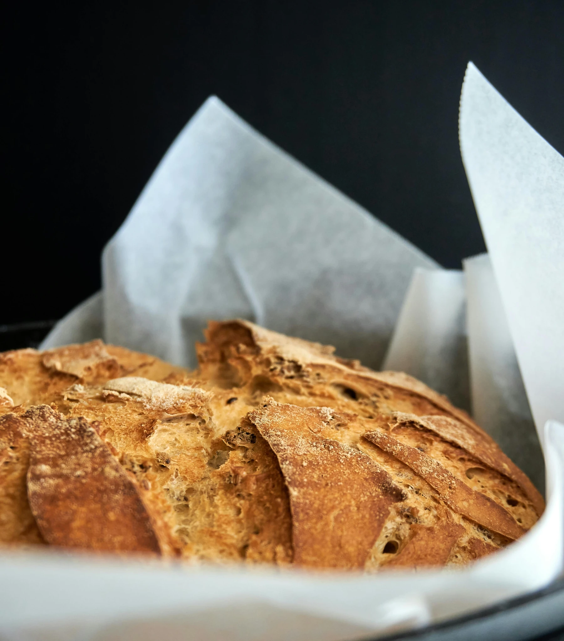 a close up of a loaf of bread in a basket, by Tom Wänerstrand, pexels contest winner, parchment paper, upper body close - up, thumbnail, recipe