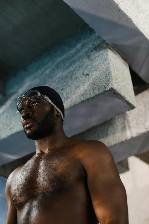 a shirtless man holding a skateboard under a bridge, by Jessie Alexandra Dick, pexels contest winner, in a swimming pool, black skin, looking serious, wearing shiny black goggles
