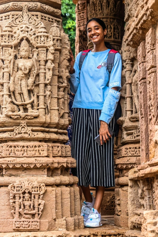 a woman standing in the doorway of a building, inspired by Steve McCurry, pexels contest winner, bengal school of art, temple ruins, she is wearing streetwear, highly detailed carvings, blue