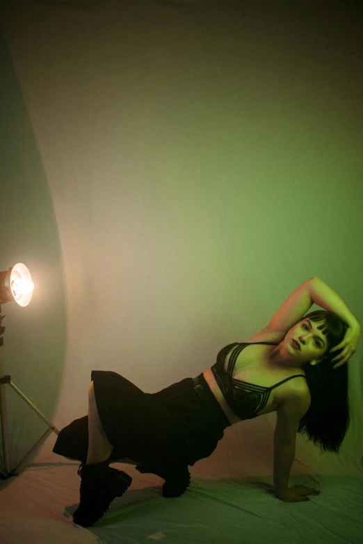 a woman laying on top of a bed under a green light, inspired by Nan Goldin, unsplash, model standing pose, betty page, low quality photo, studio!! portrait lighting
