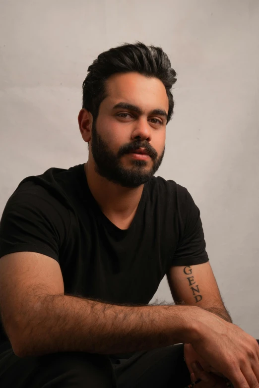 a man sitting in front of a laptop computer, a character portrait, by Alejandro Obregón, pexels contest winner, hurufiyya, with a beard and a black shirt, androgynous person, studio photo, with black hair